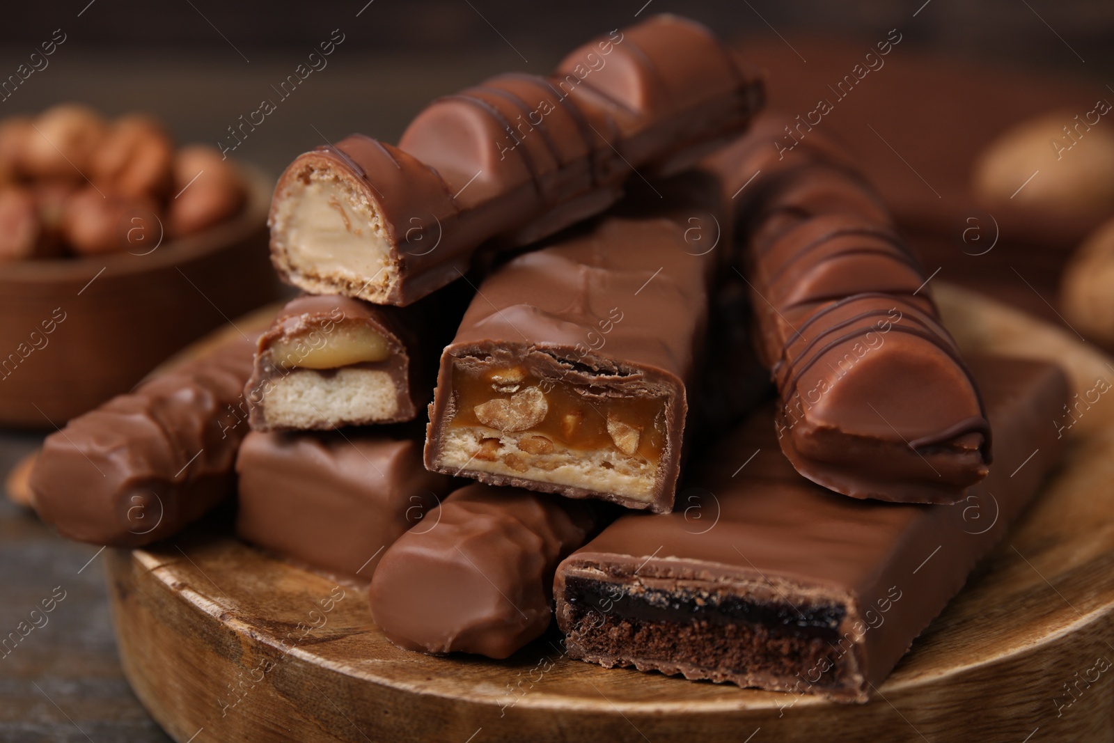 Photo of Pieces of different tasty chocolate bars on wooden board, closeup