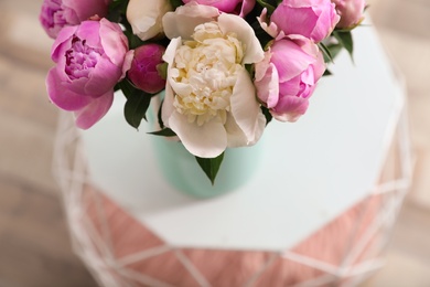 Photo of Vase with bouquet of beautiful peonies on table, above view