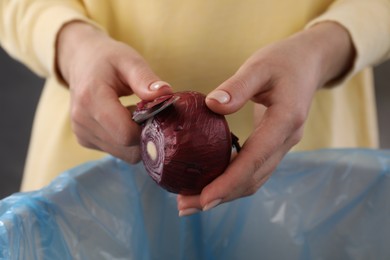 Photo of Woman peeling fresh onion with knife above garbage bin indoors, closeup