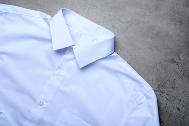 Photo of Stylish white shirt on grey stone table, top view. Dry-cleaning service