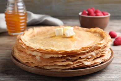 Photo of Stack of delicious crepes with melting butter on wooden table