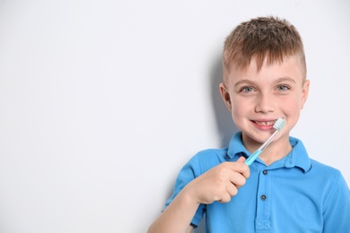 Portrait of little boy with toothbrush on light background. Space for text