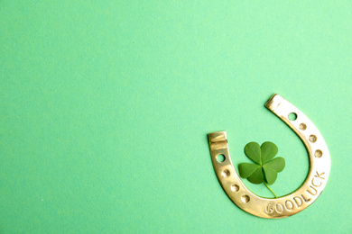 Photo of Clover leaf and horseshoe on green background, flat lay with space for text. St. Patrick's Day celebration