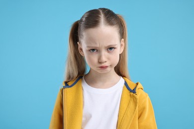 Portrait of sad girl on light blue background