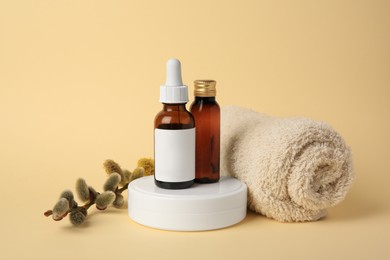 Photo of Cosmetic products, rolled towel and willow branch on beige background