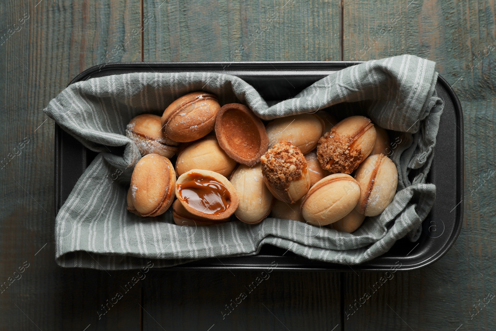 Photo of Freshly baked homemade walnut shaped cookies with condensed milk on wooden table, top view