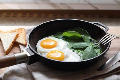 Photo of Delicious fried egg with spinach served on wooden table, closeup