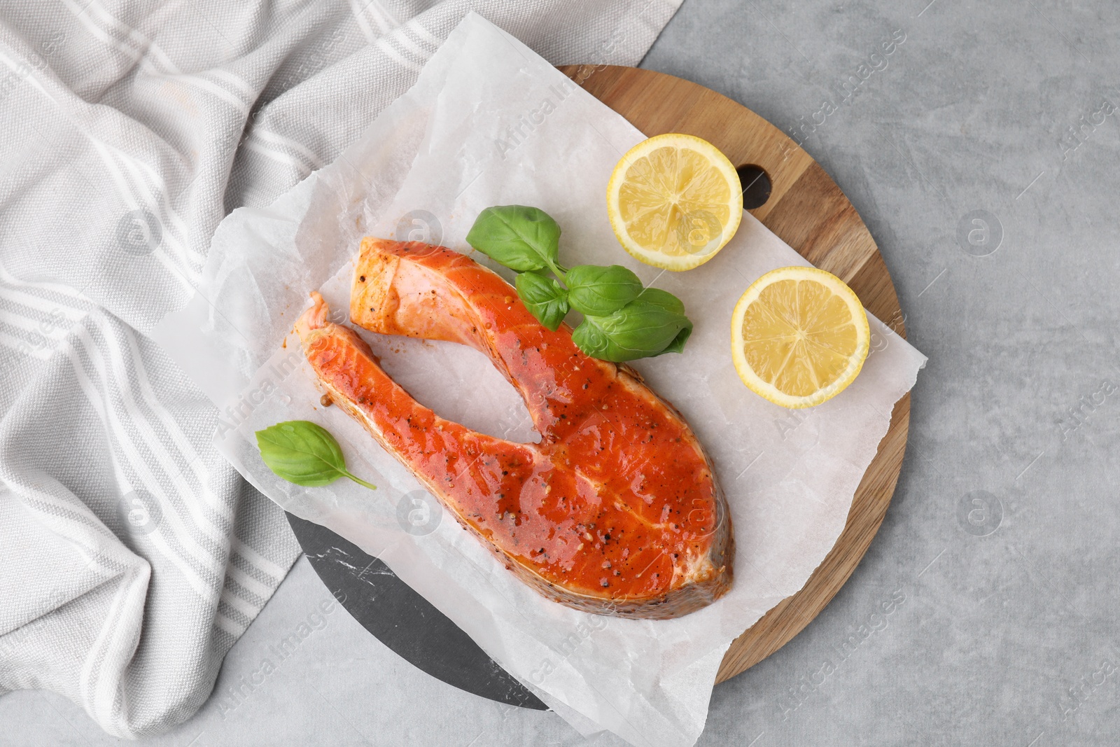 Photo of Fresh marinade, fish, lemon and basil on grey table, top view