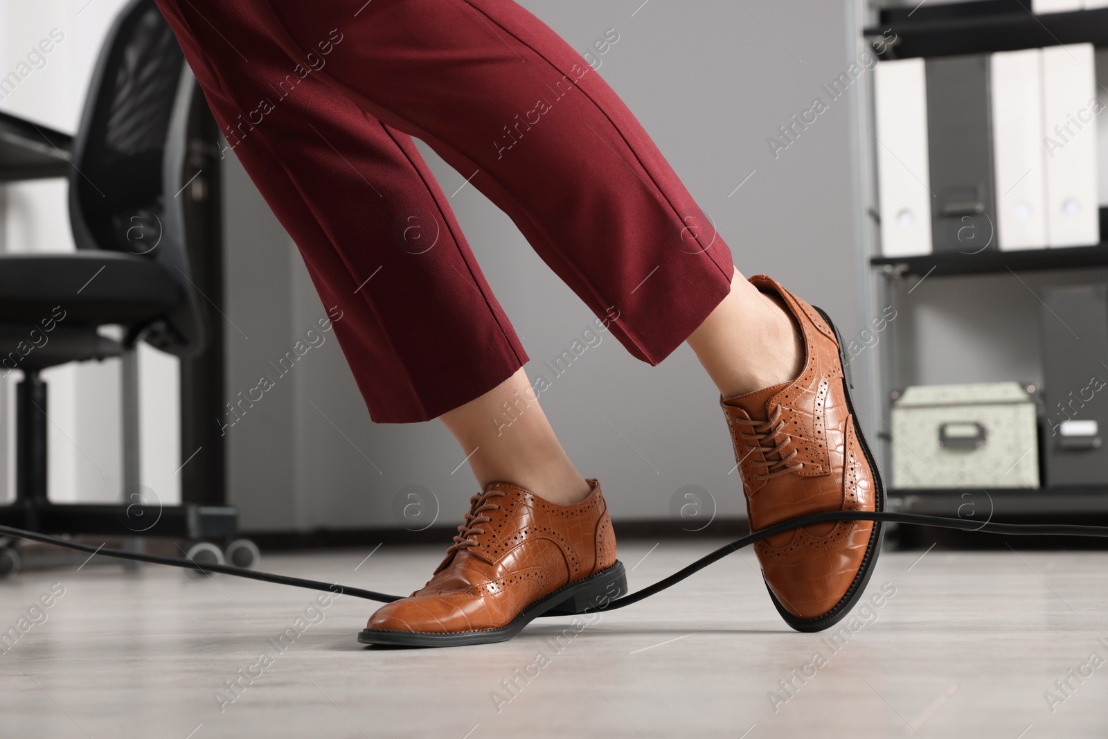 Photo of Woman tripping over cable in office, closeup