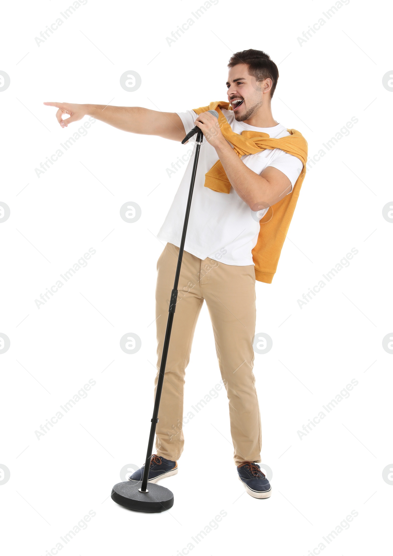 Photo of Young handsome man in casual clothes singing with microphone on white background