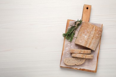 Fresh crispy ciabatta with rosemary on white wooden table, top view. Space for text