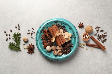 Photo of Different aromatic spices and fir branches on light textured table, flat lay