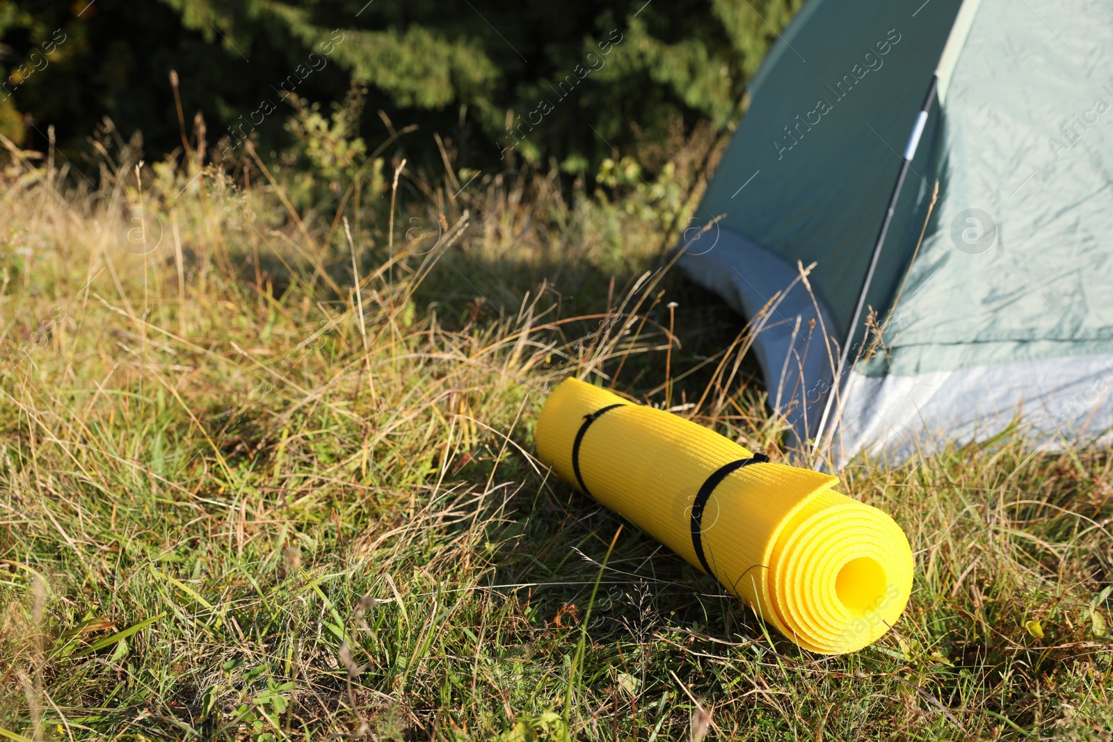 Photo of Sleeping mat near camping tent outdoors. Tourism equipment