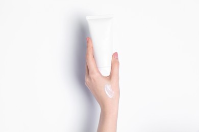 Woman with tube of cream on white background, closeup