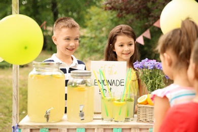 Photo of Little kids selling natural lemonade at stand in park