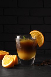 Photo of Tasty refreshing drink with coffee and orange juice on grey table against dark background