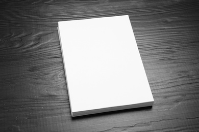 Stack of blank paper sheets for brochure on black wooden background. Mock up