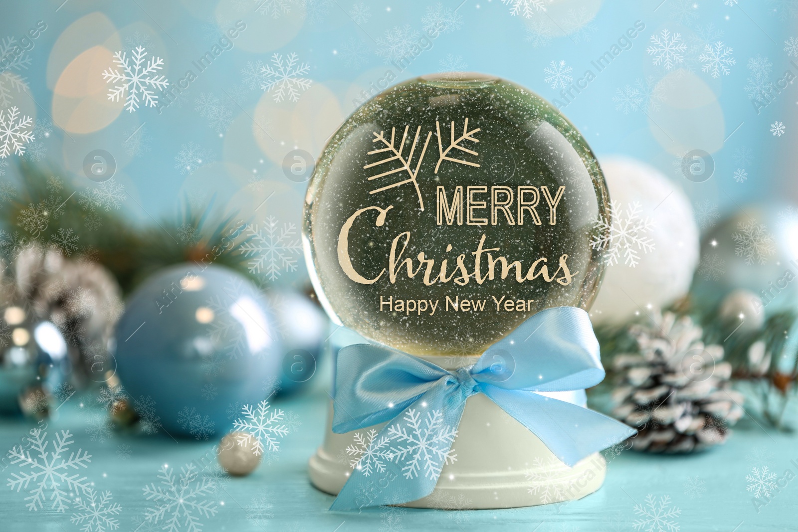 Beautiful snow globe with phrase Merry Christmas and decor on light blue table, closeup Image of Beautiful snow globe with phrase Merry Christmas and decor on light blue table, closeup