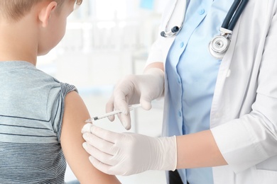 Doctor vaccinating little boy in hospital