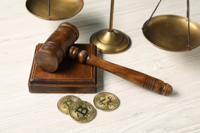 Law concept. Gavel, scales and bitcoins on white wooden table, closeup