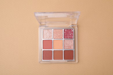 Photo of Beautiful eye shadow palette on beige background, top view