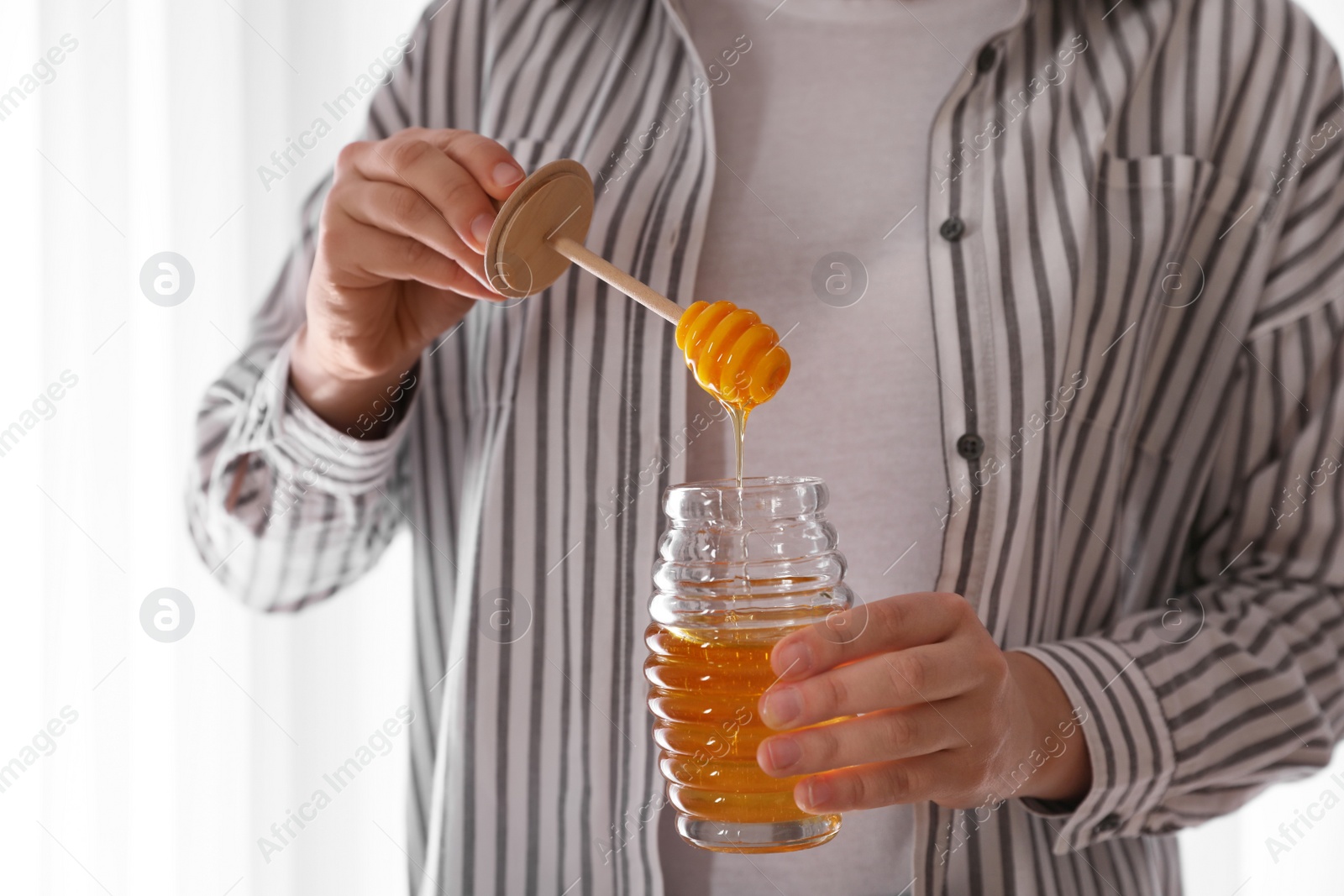 Photo of Woman with honey and dipper indoors, closeup