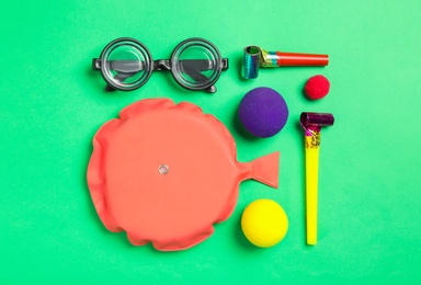 Photo of Different clown's accessories on green background, flat lay