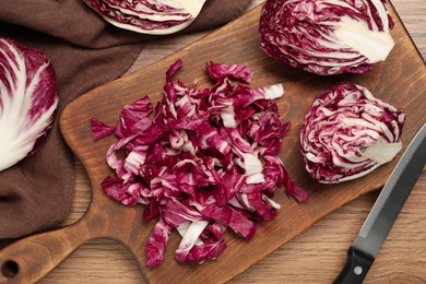 Photo of Cut radicchio and knife on wooden table, flat lay