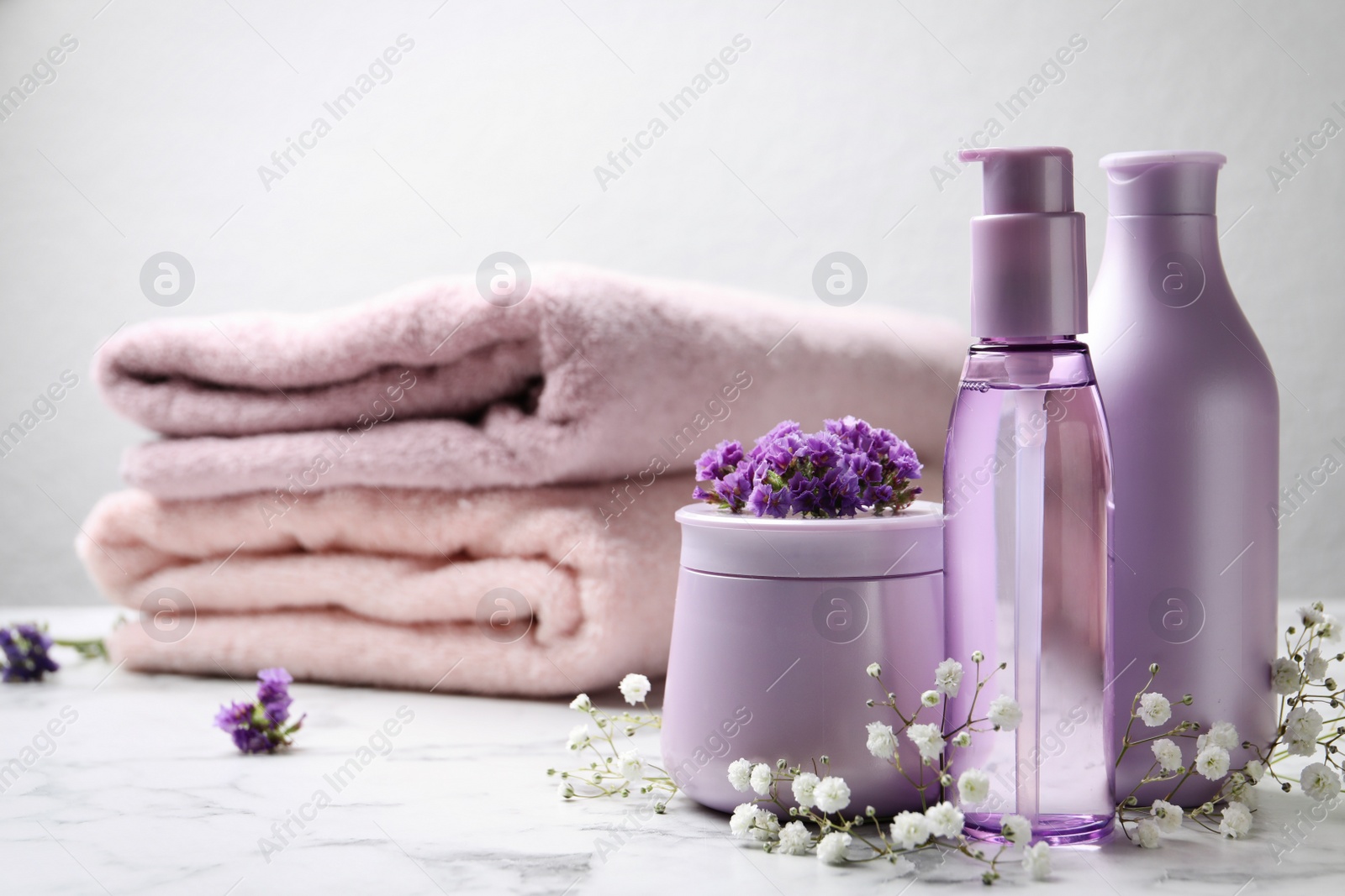 Photo of Set of hair cosmetic products and flowers on white marble table