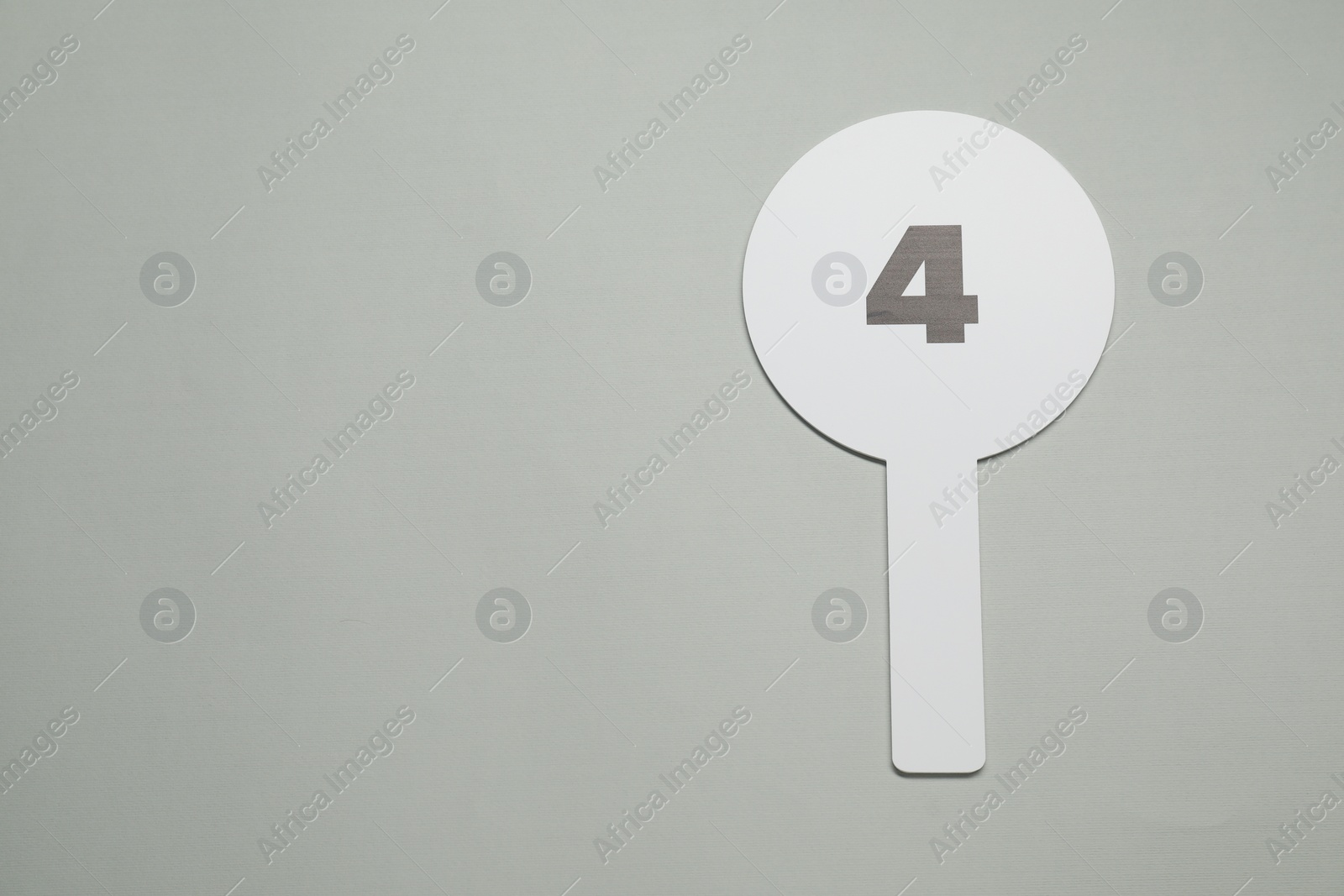 Photo of Auction paddle with number 4 on light grey background, top view. Space for text