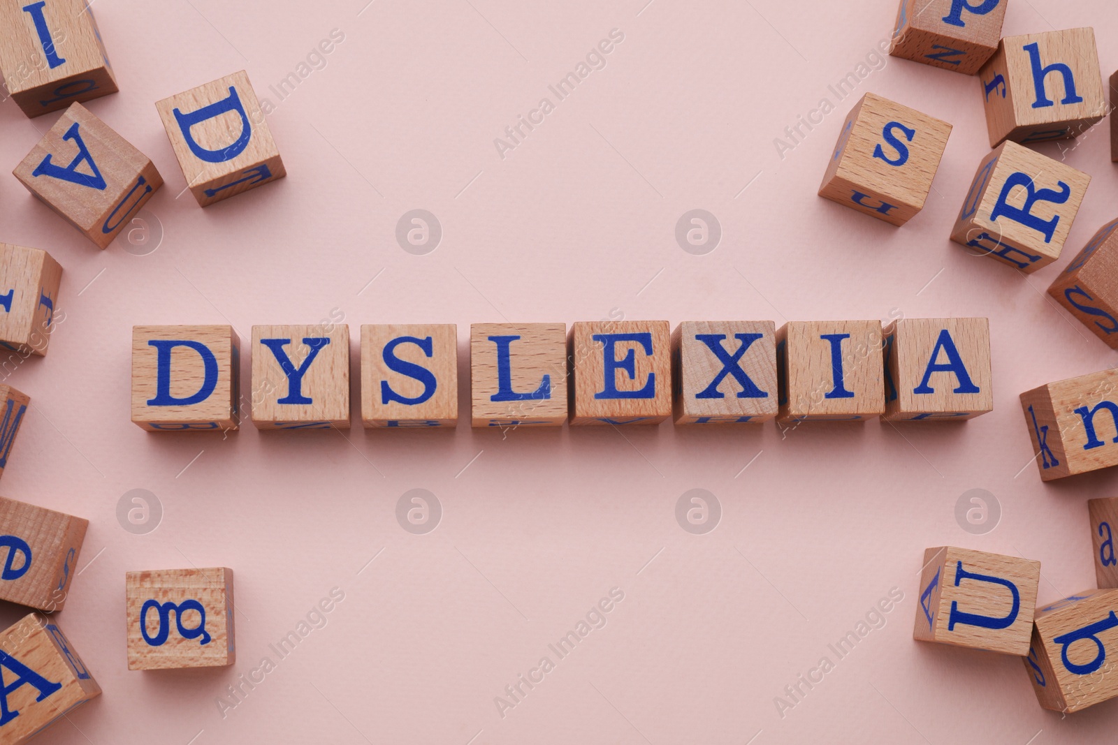 Photo of Wooden cubes with word Dyslexia on beige background, flat lay