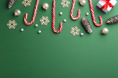 Photo of Flat lay composition with candy canes and Christmas decor on green background. Space for text