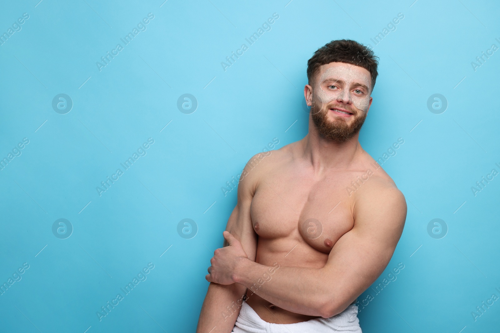 Photo of Handsome man with facial mask on his face against light blue background, space for text