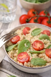 Delicious quinoa salad with tomatoes, beans and spinach leaves served on table, closeup