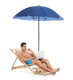 Photo of Young man with laptop on sun lounger under umbrella against white background. Beach accessories