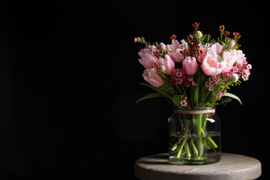 Photo of Beautiful bouquet with spring pink tulips on wooden table against black background. Space for text