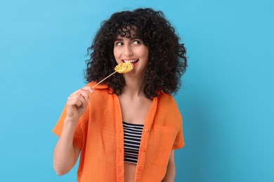 Beautiful woman with lollipop on light blue background