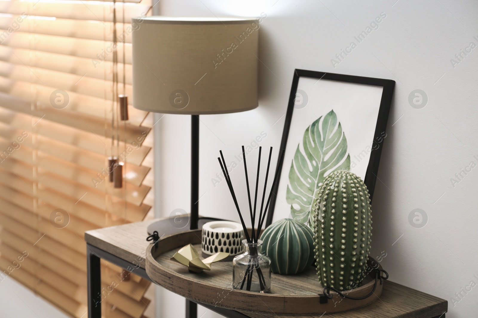 Photo of Wooden tray with decorations and lamp on table indoors