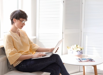 Photo of Young woman working with laptop at home