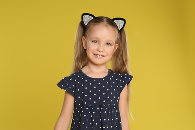 Portrait of cute little girl on yellow background