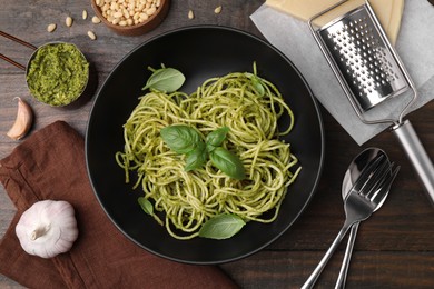 Photo of Delicious pasta with pesto sauce and basil served on wooden table, flat lay