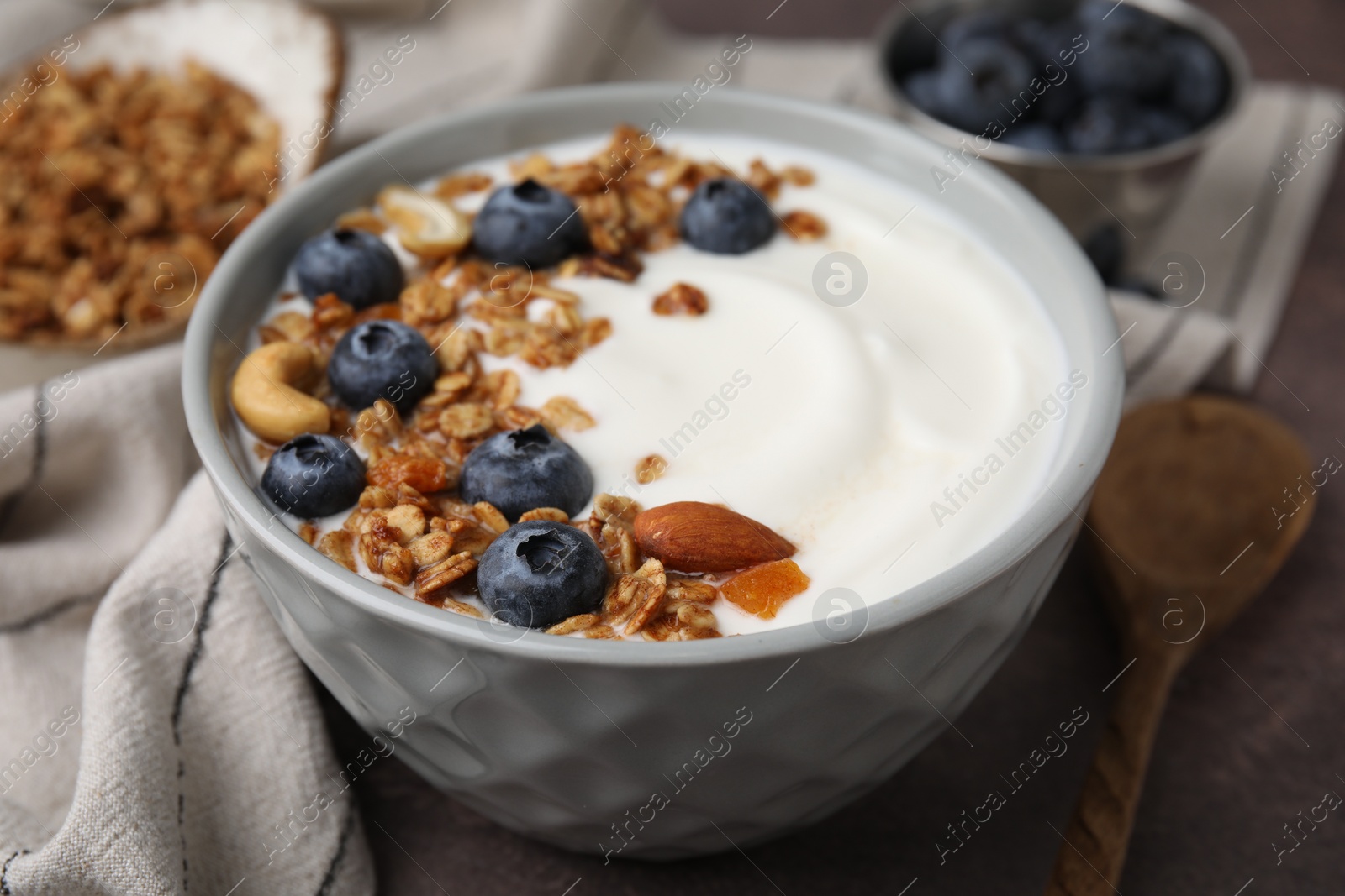 Photo of Bowl with yogurt, blueberries and granola on grey table, closeup