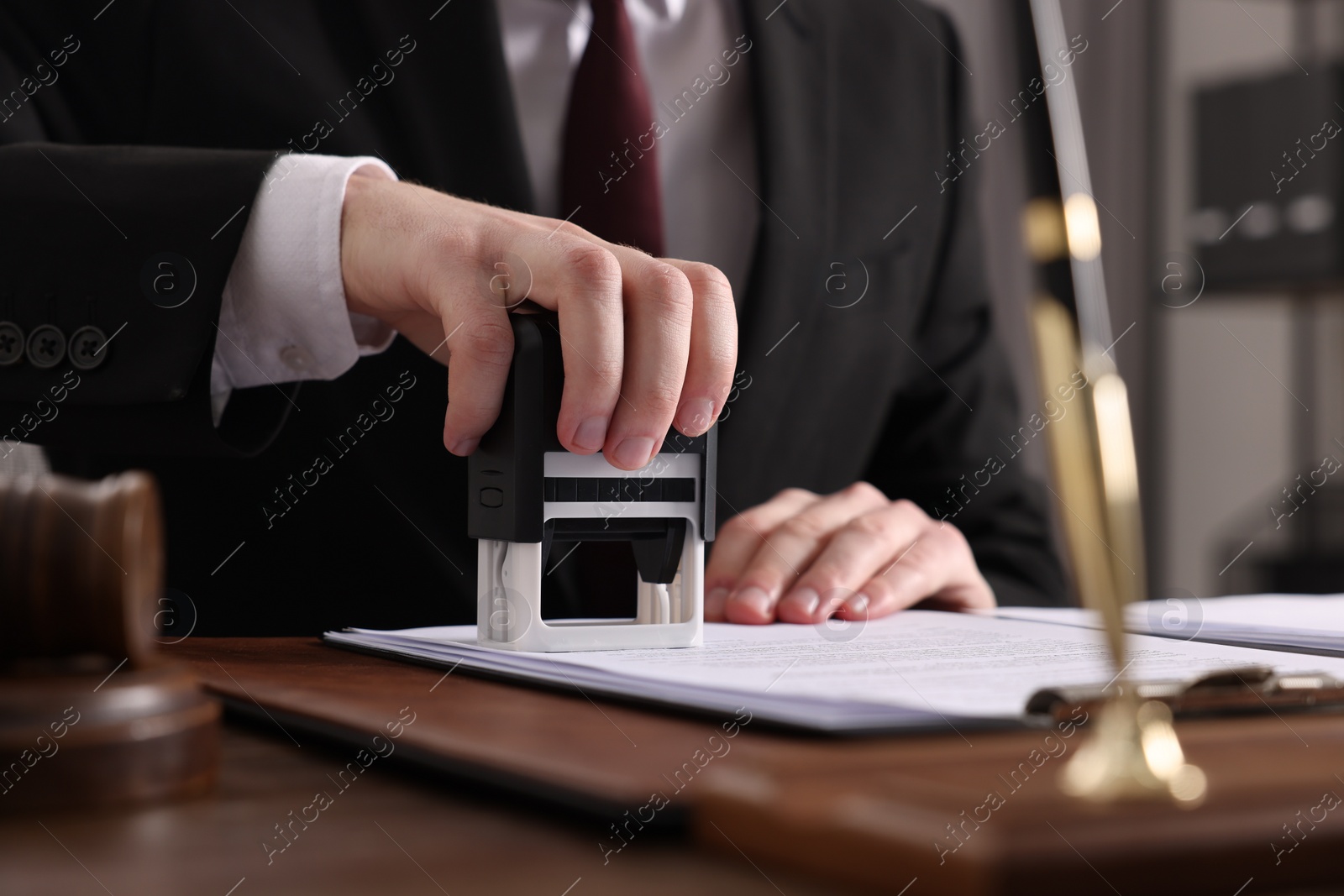 Photo of Notary stamping document at table in office, closeup