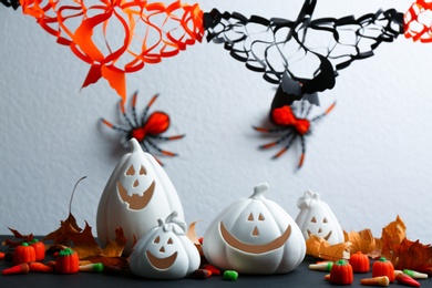 Composition with pumpkin shaped candle holders on black table against white background. Halloween decoration