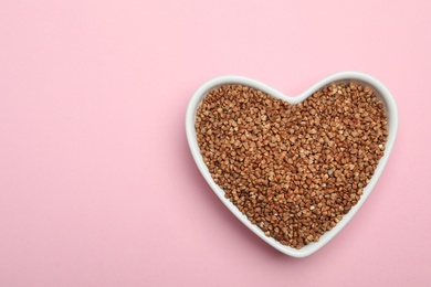 Photo of Buckwheat grains on pink background, top view. Space for text