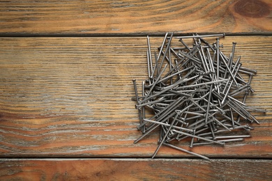 Photo of Many metal nails on wooden background, flat lay. Space for text