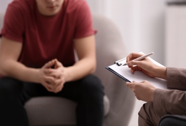 Photo of Psychotherapist working with young man in office, closeup