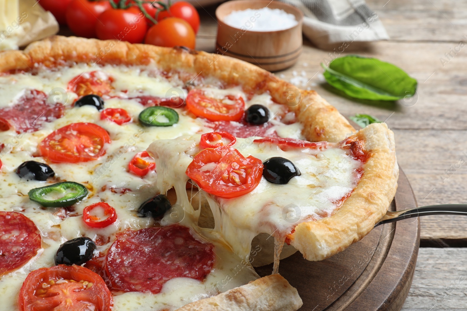 Photo of Taking slice of delicious pizza Diablo on wooden table, closeup