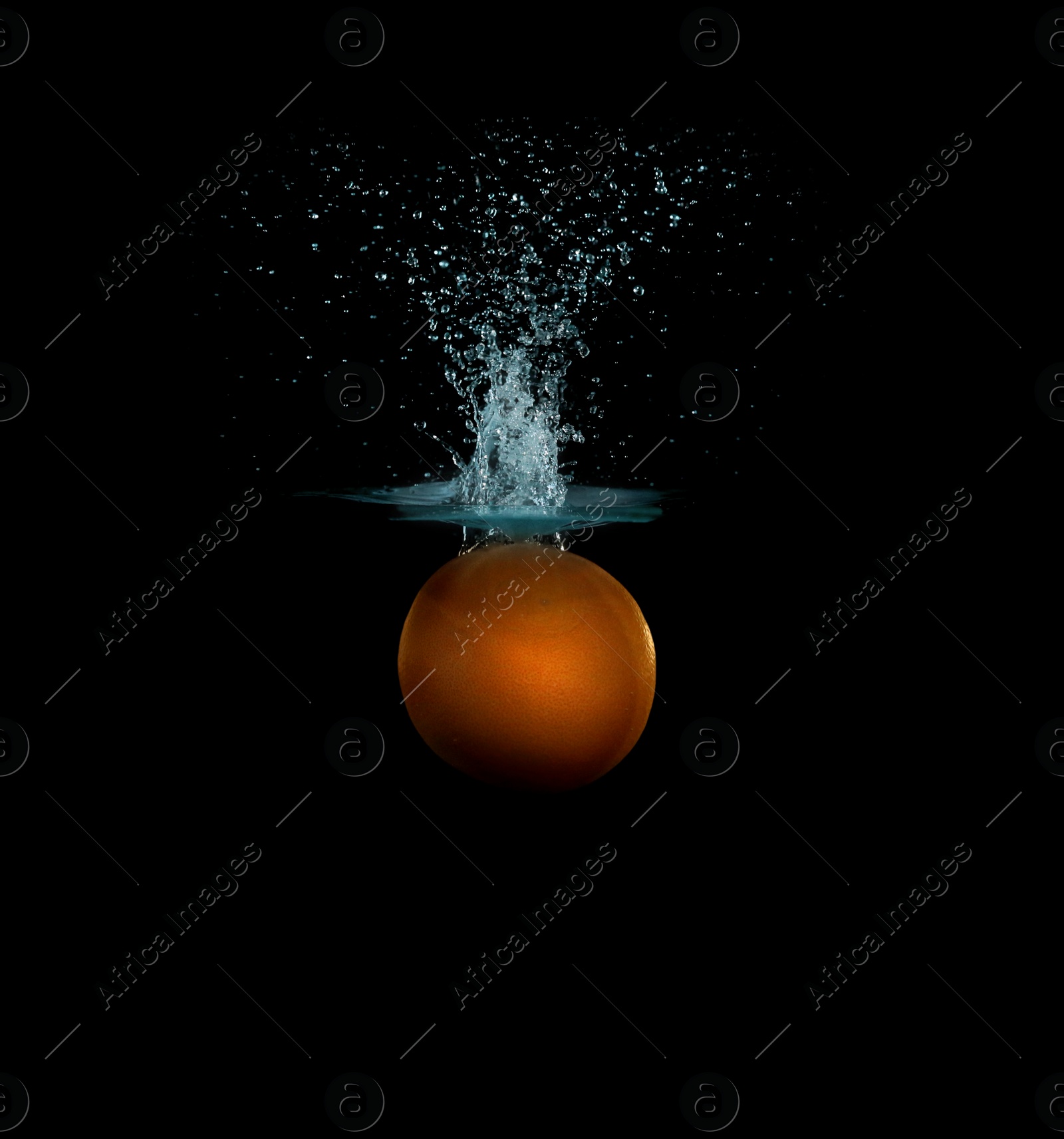 Photo of Grapefruit falling down into clear water against black background