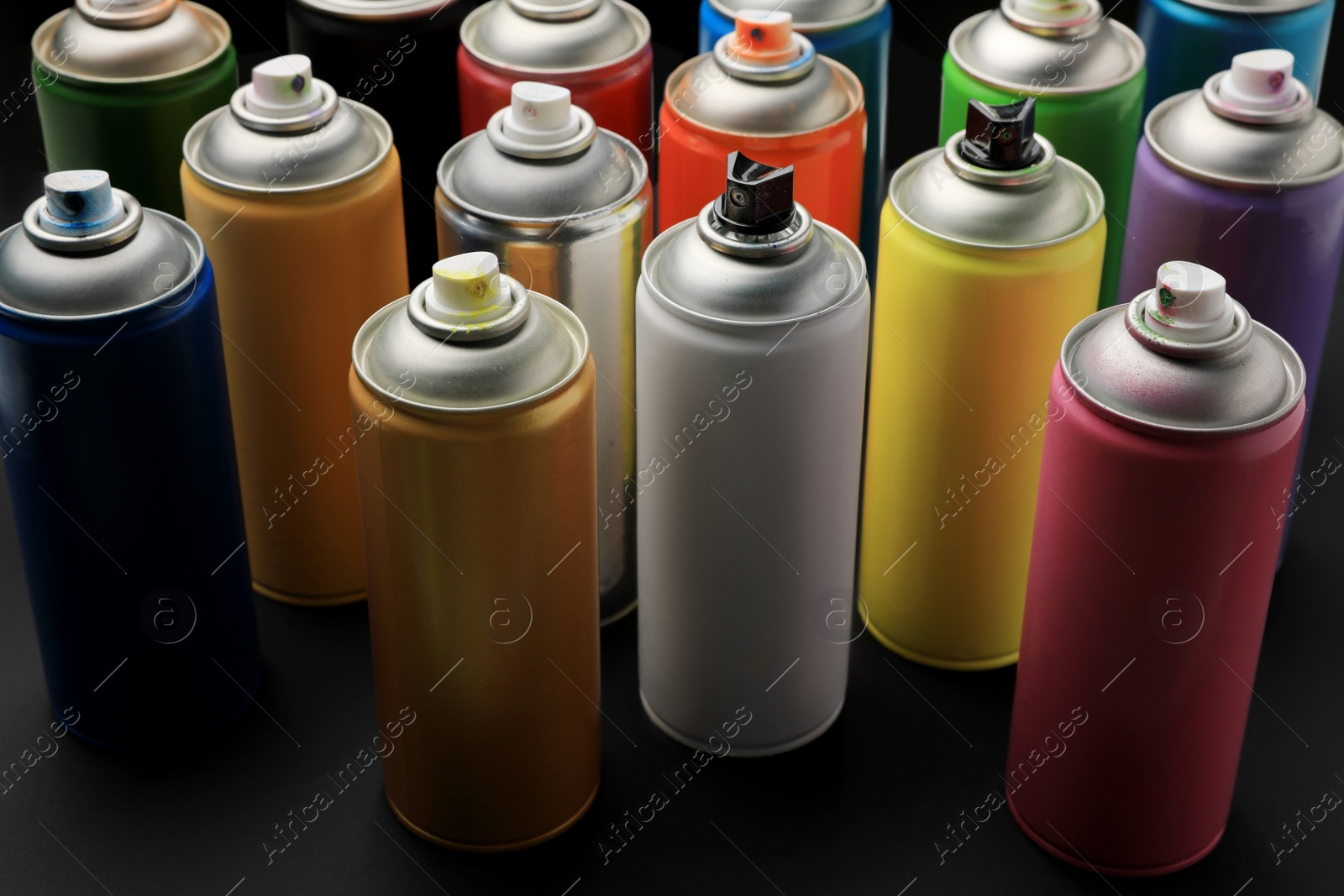 Photo of Cans of different graffiti spray paints on black background